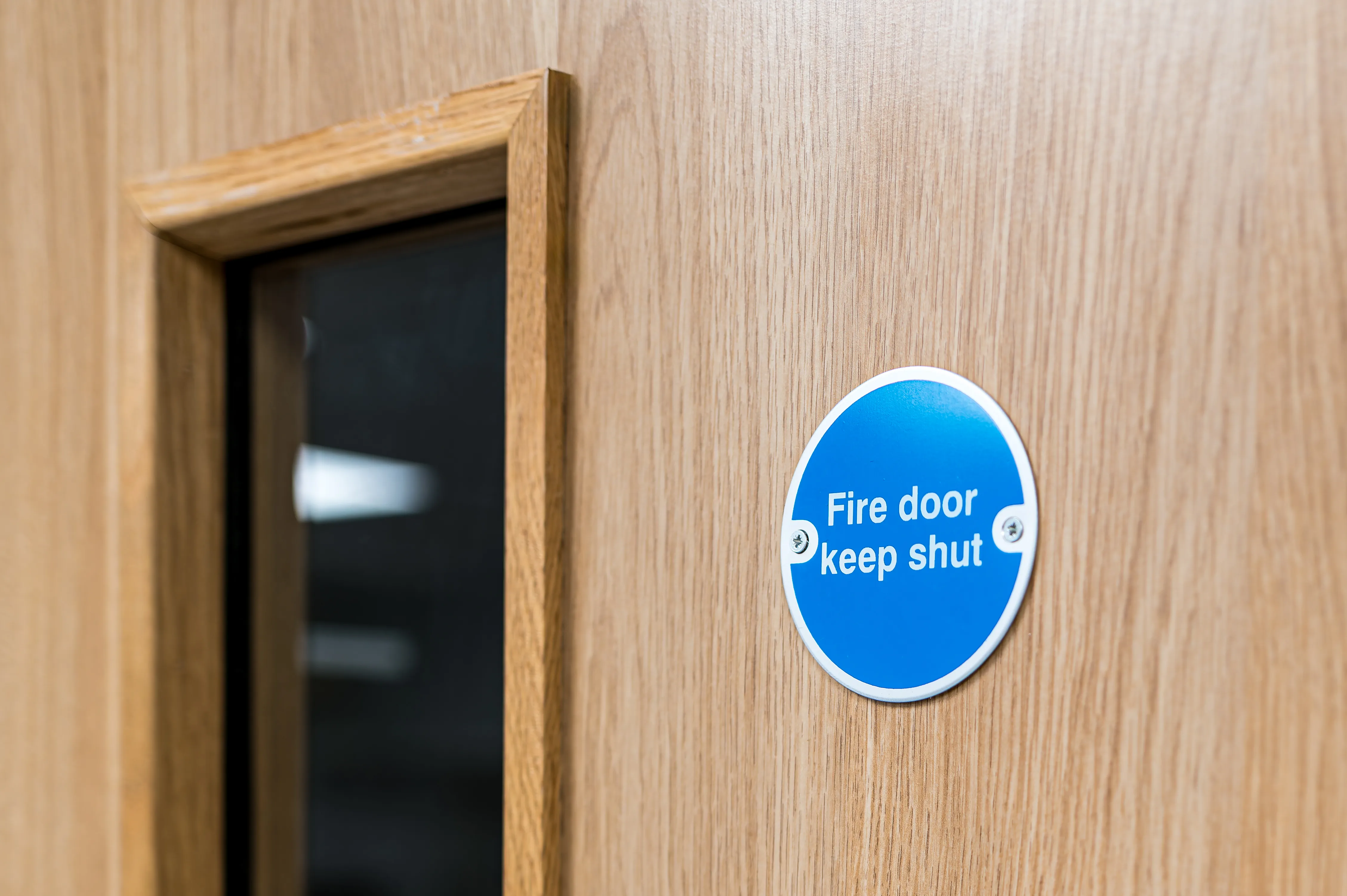 Fire door keep shut sign on wooden door showing proper fire door signage and compliance requirements